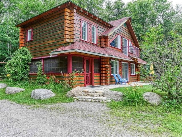 Maison en bois rond entourée d'arbres